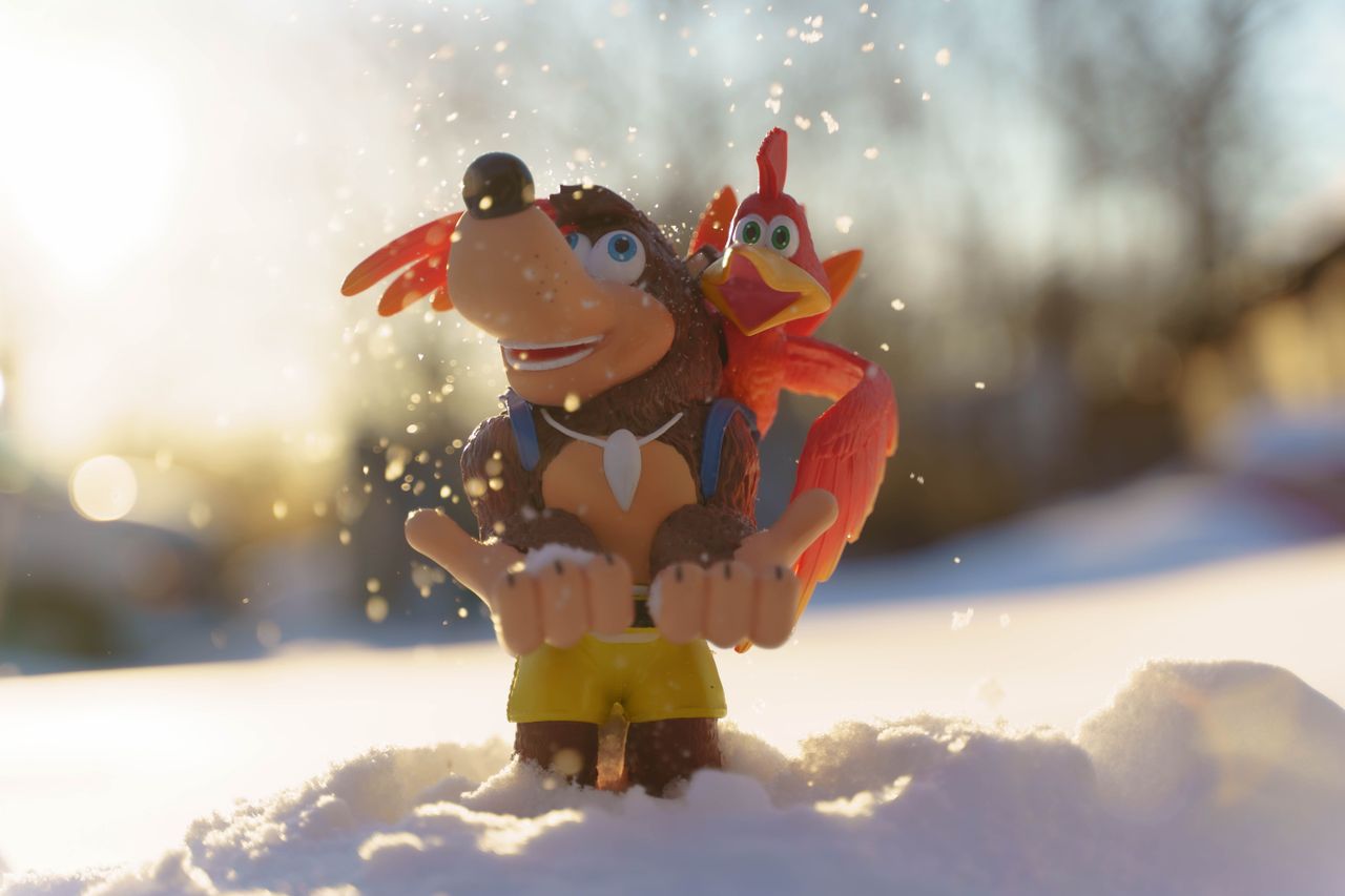 Close-up of toy figures on snow with a sunny backdrop, creating a whimsical winter scene.